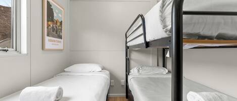 A bunk bed room with white bedding and a framed picture on the wall.