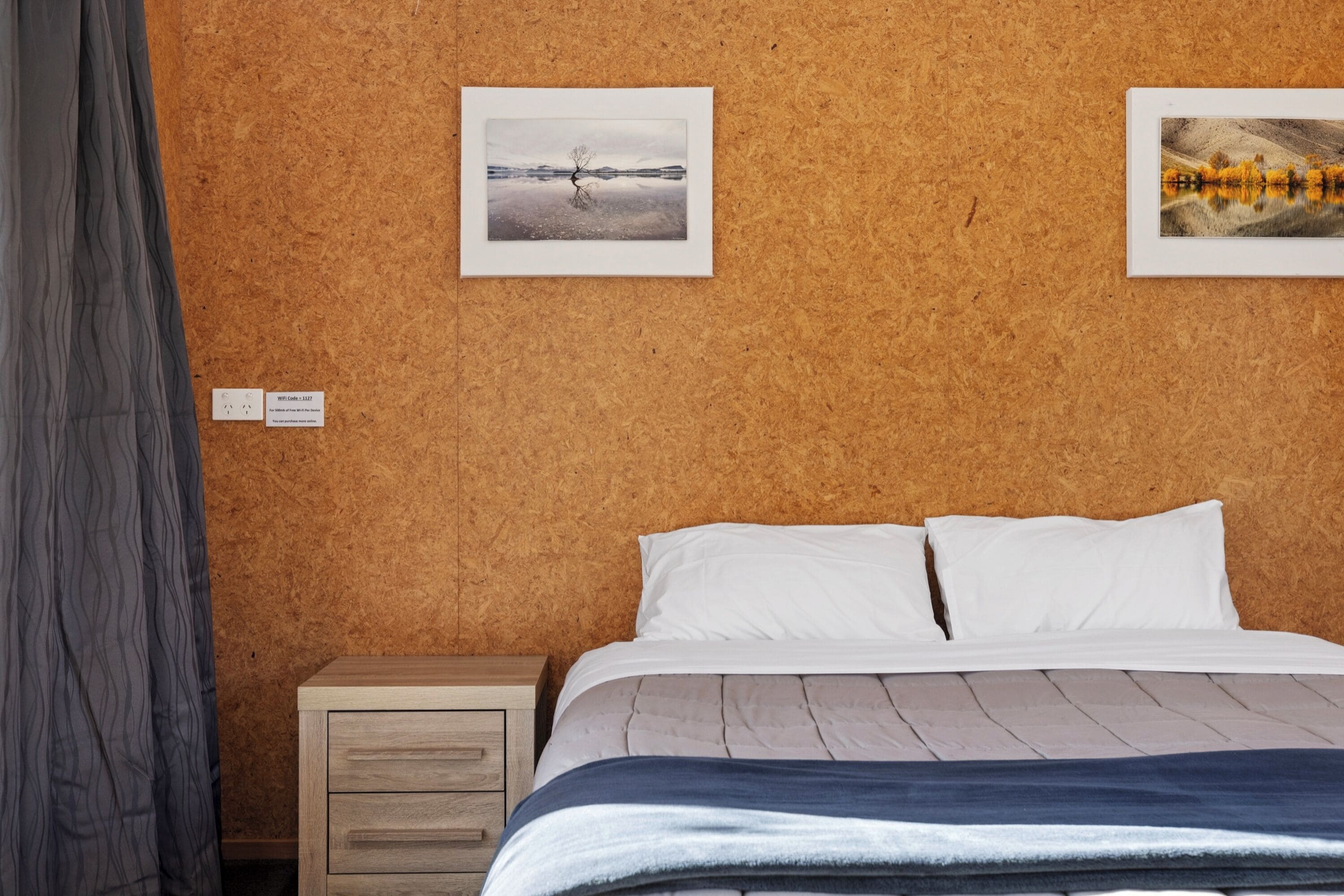 Ein Zimmer mit einem Bett, einem Nachttisch und zwei gerahmten Bildern an der Wand.