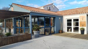 Edifici amb zona de recepció, bar i terrassa de fusta.