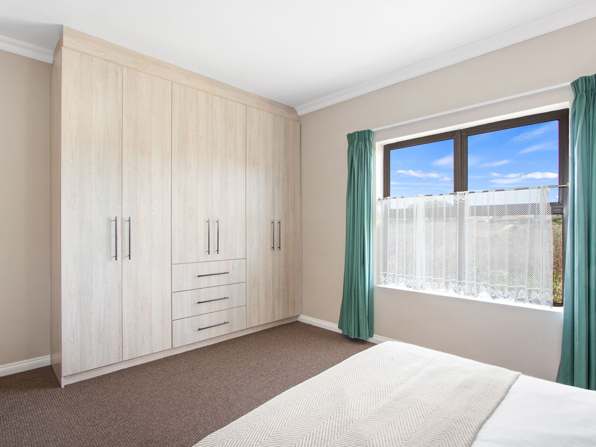 Une chambre avec une grande armoire, un lit et une fenêtre avec des rideaux.