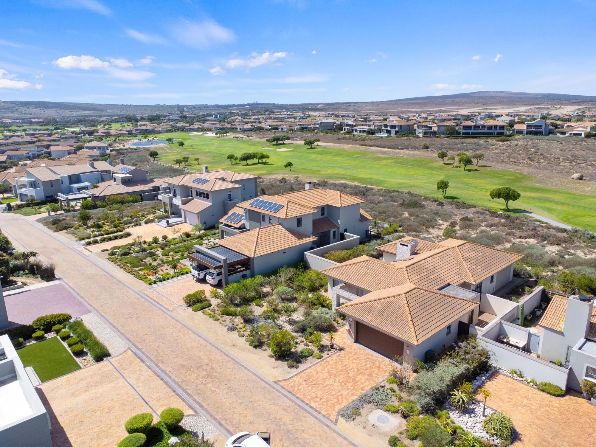 Un quartier résidentiel avec des maisons, un terrain de golf et un ciel dégagé.