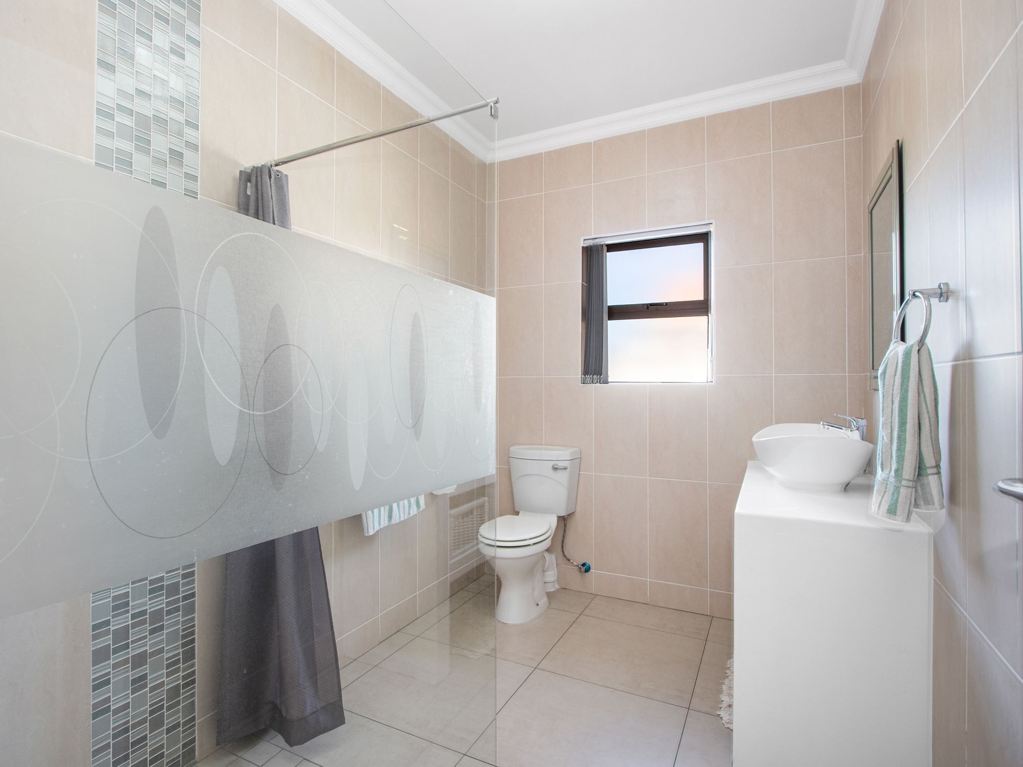 Un baño moderno con inodoro, lavamanos y zona de ducha.