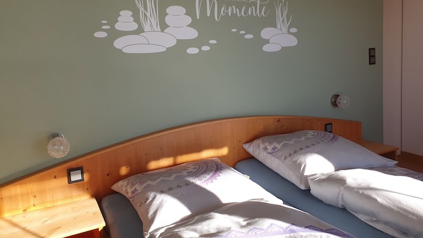 Un dormitorio con dos camas, un cabecero de madera y un adhesivo mural con pájaros y rocas.