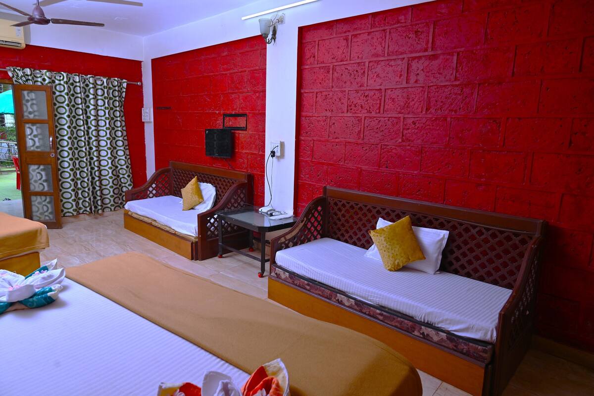 A hotel room with two single beds, a wooden headboard, a small table, and a red brick wall.