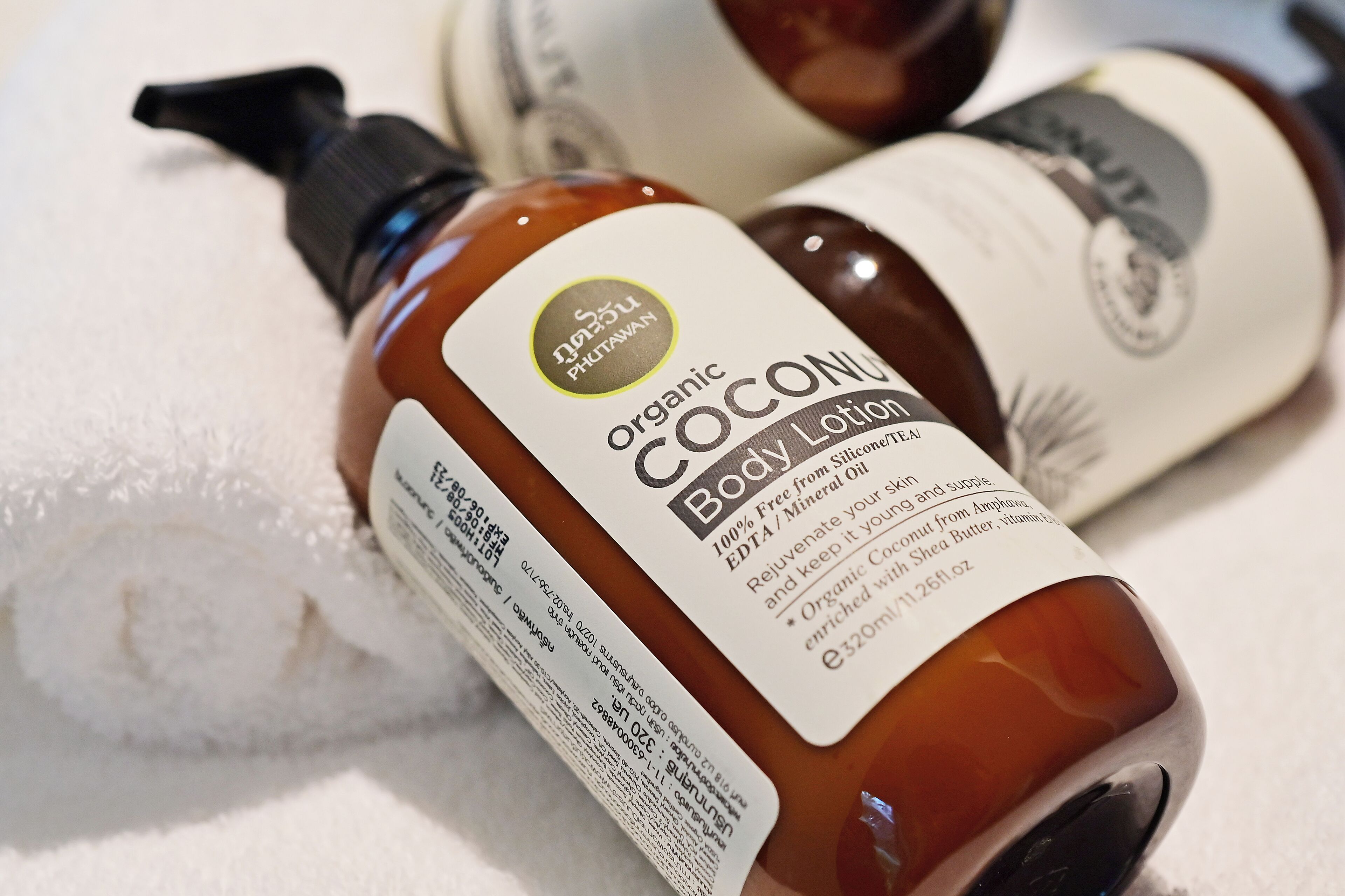 Two bottles of organic coconut body lotion on a white surface.