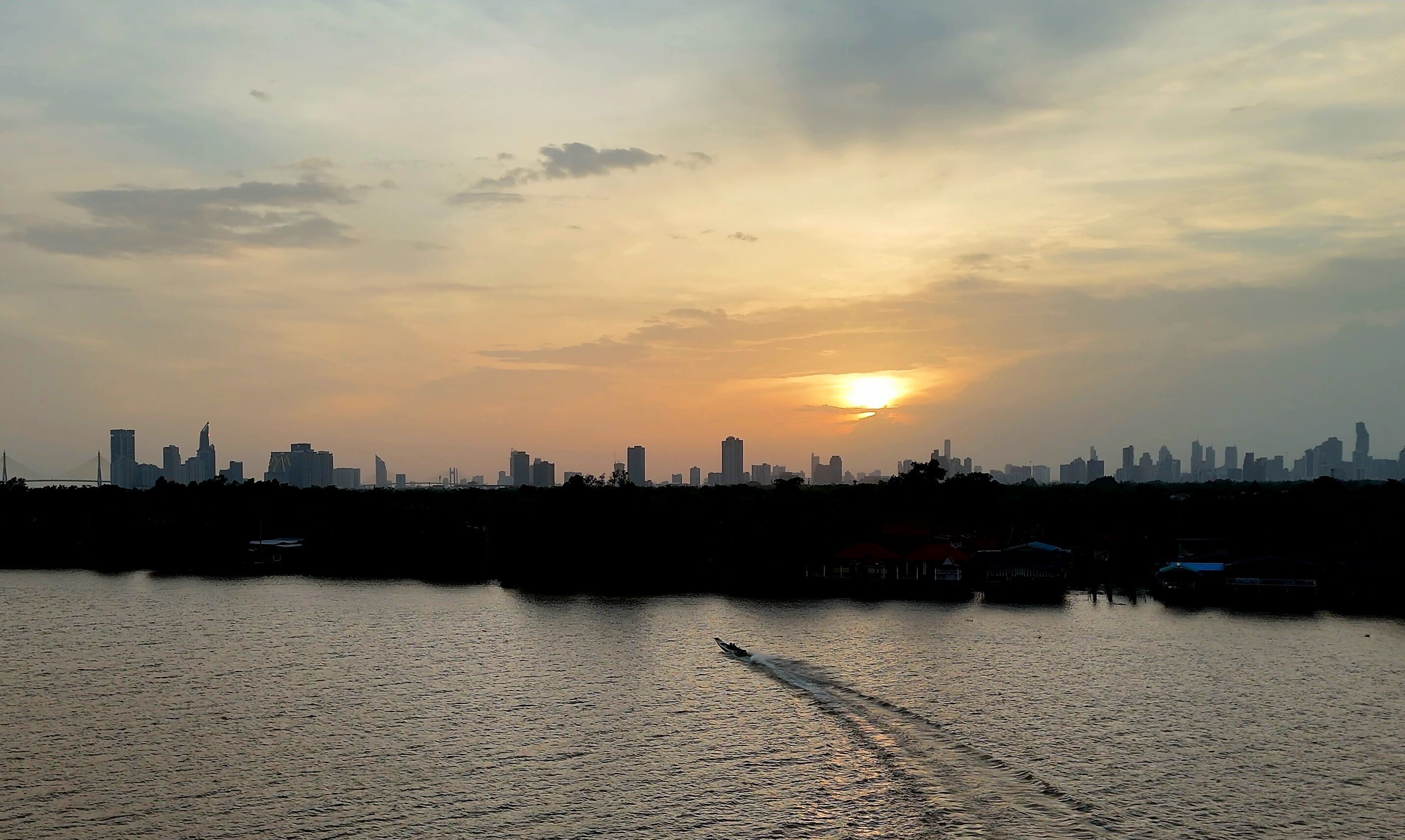 A city skyline at sunset with a body of water in the foreground.