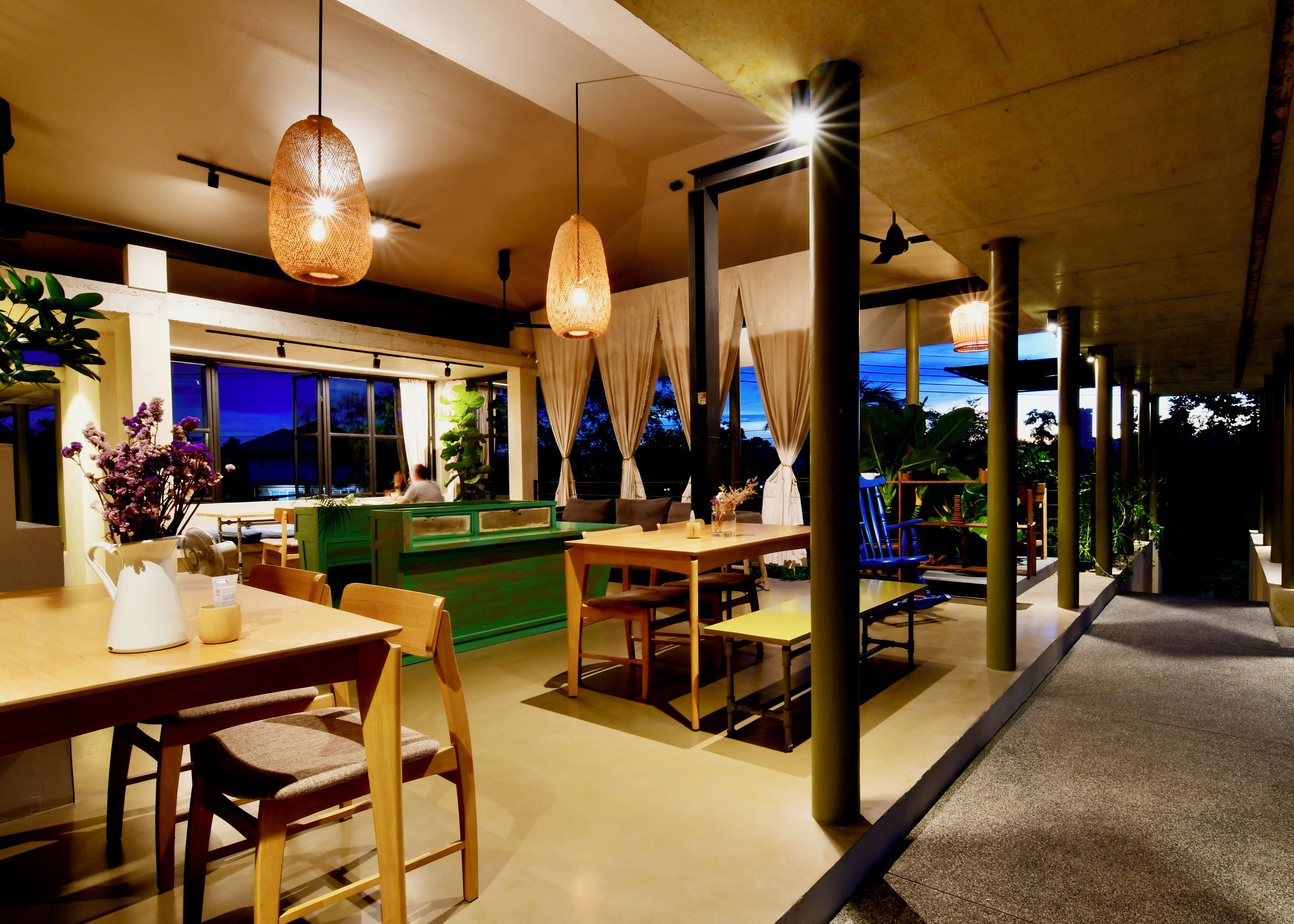 A modern dining area with wooden furniture, hanging lights, and a view of the outdoors.
