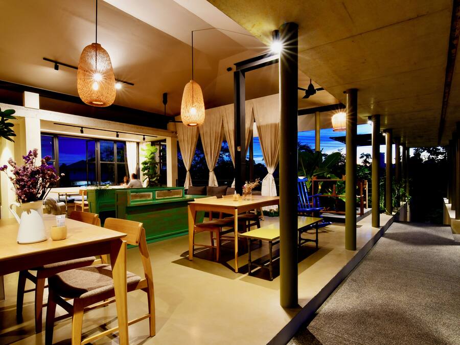 A modern dining area with wooden furniture, hanging lights, and a view of the outdoors.