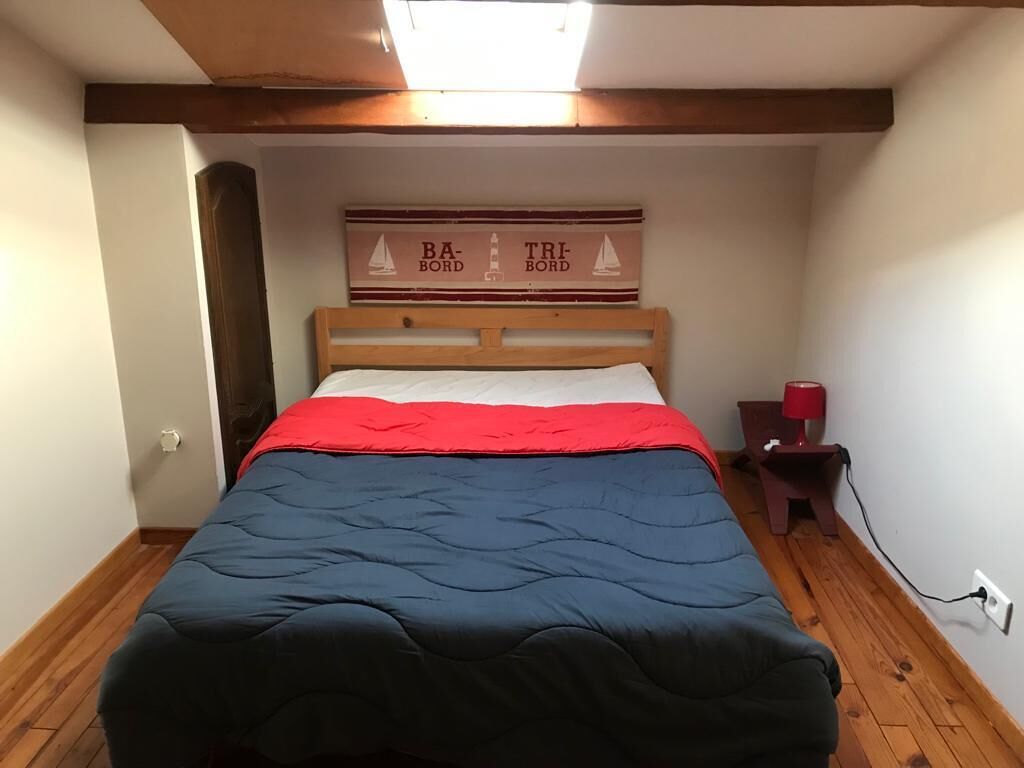 A bedroom with a bed, a nightstand, a lamp, and a wall decoration.