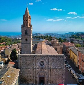 A historic church with a prominent bell tower and a circular window on the facade. - Hotel Astoria (Pineto)