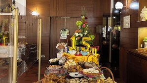 A buffet setup with various food items and drinks, a mirror reflecting the room, and a '15th' balloon decoration. - Hotel Astoria (Pineto)