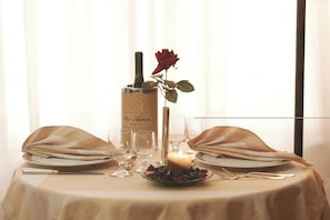 Una mesa para dos, con una vela, una botella y una rosa.