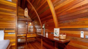 A wooden cabin interior with a bed, wooden benches, a table with a basket, and a wall-mounted thermostat. - Chalet Style 2BR Pool Villa Pasak 1 (Choeng Thale)
