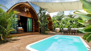 A pool area with a wooden deck, a covered seating area, and lush tropical vegetation. - Chalet Style 2BR Pool Villa Pasak 1 (Choeng Thale)