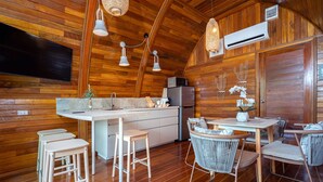 A wooden interior with a kitchen area, bar stools, and a dining table with chairs. - Chalet Style 2BR Pool Villa Pasak 1 (Choeng Thale)