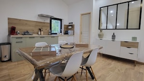 Eine moderne Küche mit Holzausziehtisch, einem Esstisch mit Stühlen und einem großen Spiegel über der Arbeitsplatte.