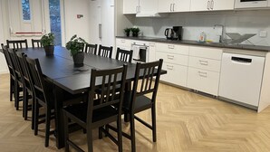 Une cuisine moderne avec des meubles blancs, une table à manger noire et des chaises en bois. On y trouve un four à micro-ondes, une machine à café et un lave-vaisselle.