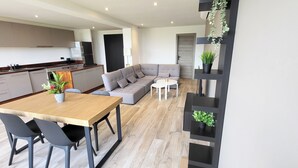Una cocina moderna con comedor, un sofá gris y una mesa pequeña.