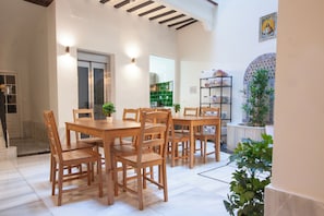 A dining area with wooden tables and chairs, a potted plant, and a tiled floor. - Hostel Ibarra by Bossh! Hotels (Seville)