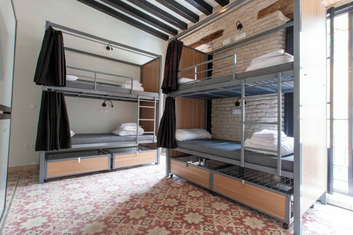 A bunk bed room with a patterned floor, a brick wall, and a window.