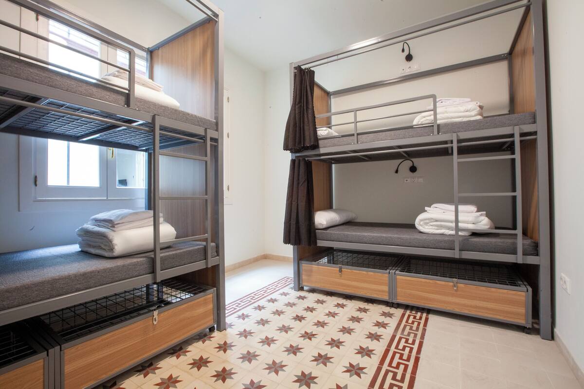 Two bunk beds with storage drawers, a patterned rug, and a window with curtains.