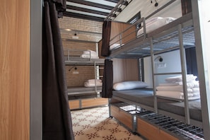 A bunk bed room with a brick wall, a wooden floor, and a curtain. - Hostel Ibarra by Bossh! Hotels (Seville)
