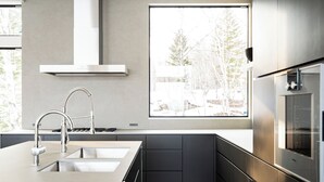 Cocina moderna con un lavamanos de acero inoxidable, horno empotrado y ventana con vistas al exterior.