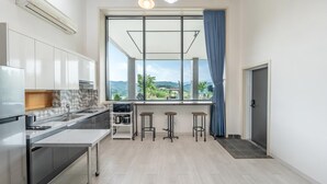 Una cucina moderna con un'ampia finestra, piano cottura integrato e un angolo bar con sgabelli.
