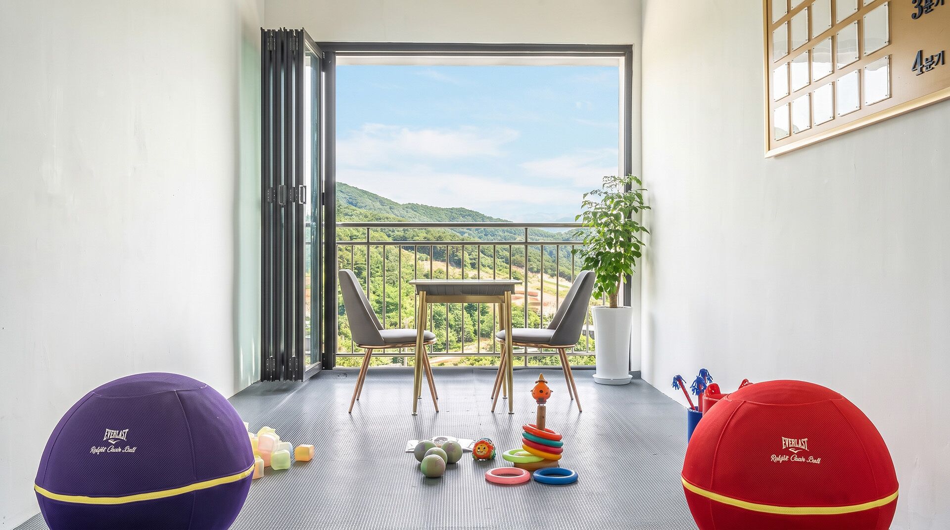 Een balkon met een tafel, stoelen, een potplant en kinderspeelgoed.