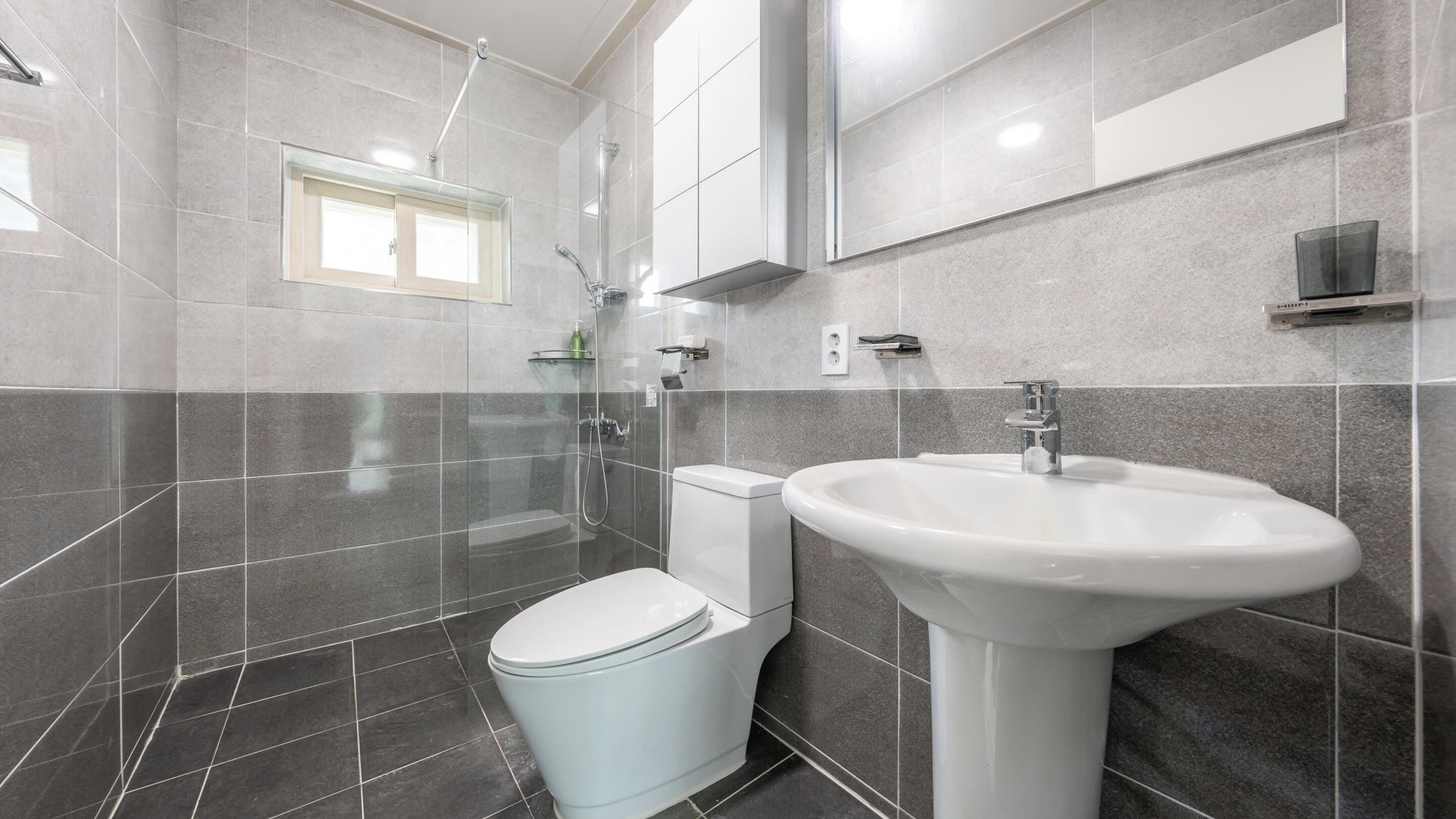 A modern bathroom with a toilet, sink, and shower.
