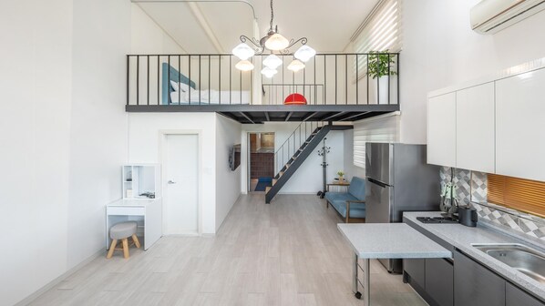 A modern kitchen with a built-in stove, a sink, and a dining area with a table and chairs. - Gapyeong Nomadrium Poolvilla Pension (Gapyeong)