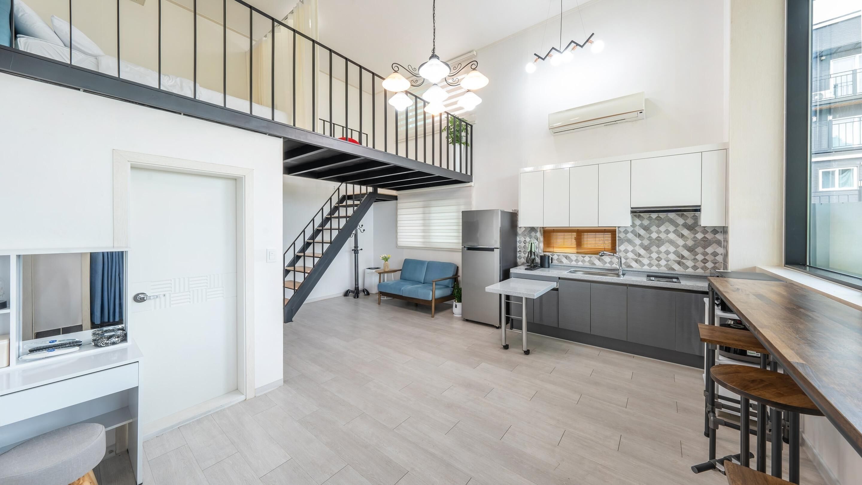 A modern apartment with a kitchen, dining area, and a staircase leading to a loft.