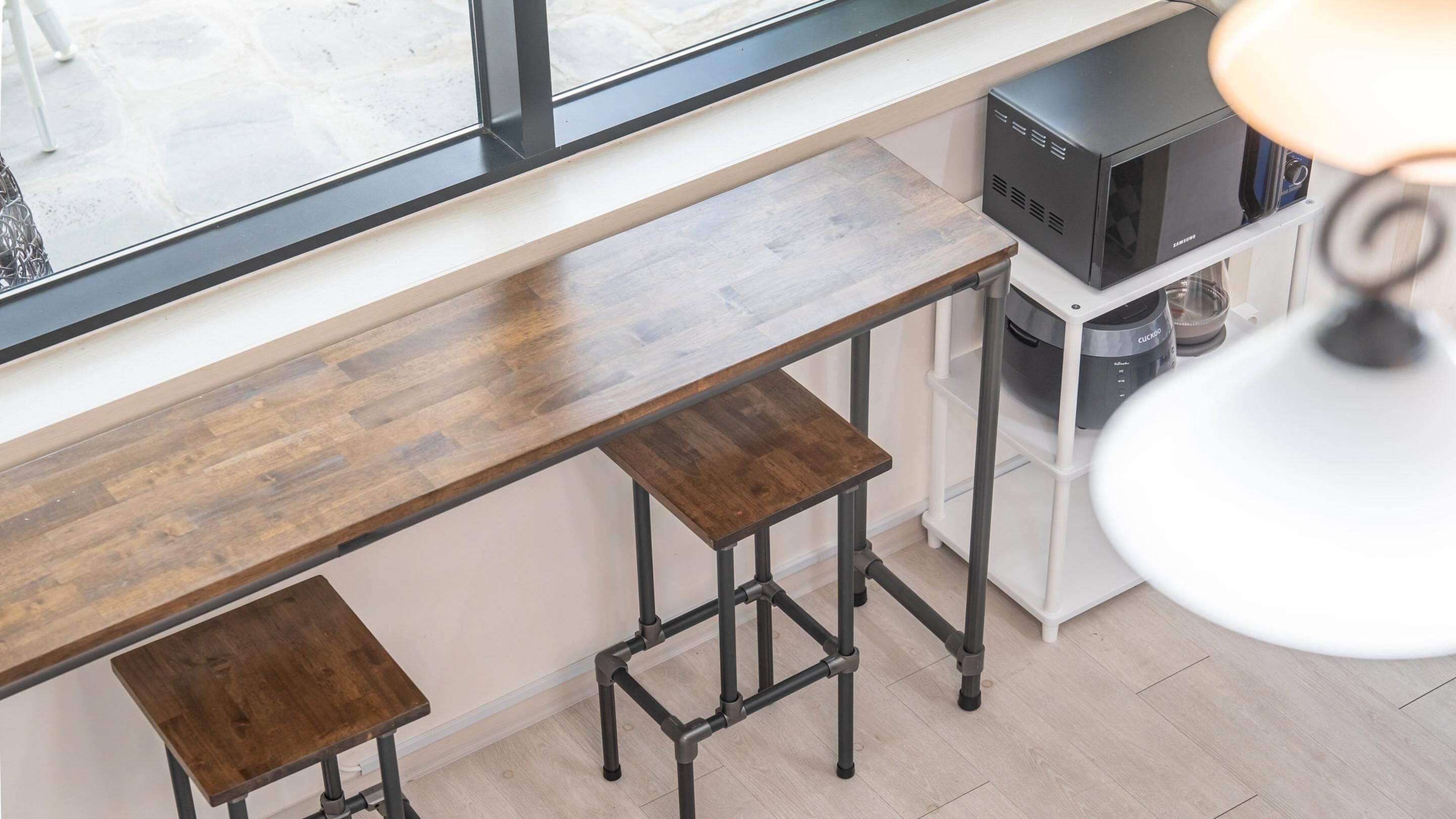 Een keuken met een houten aanrecht, twee krukken, een magnetron en een koffieapparaat.