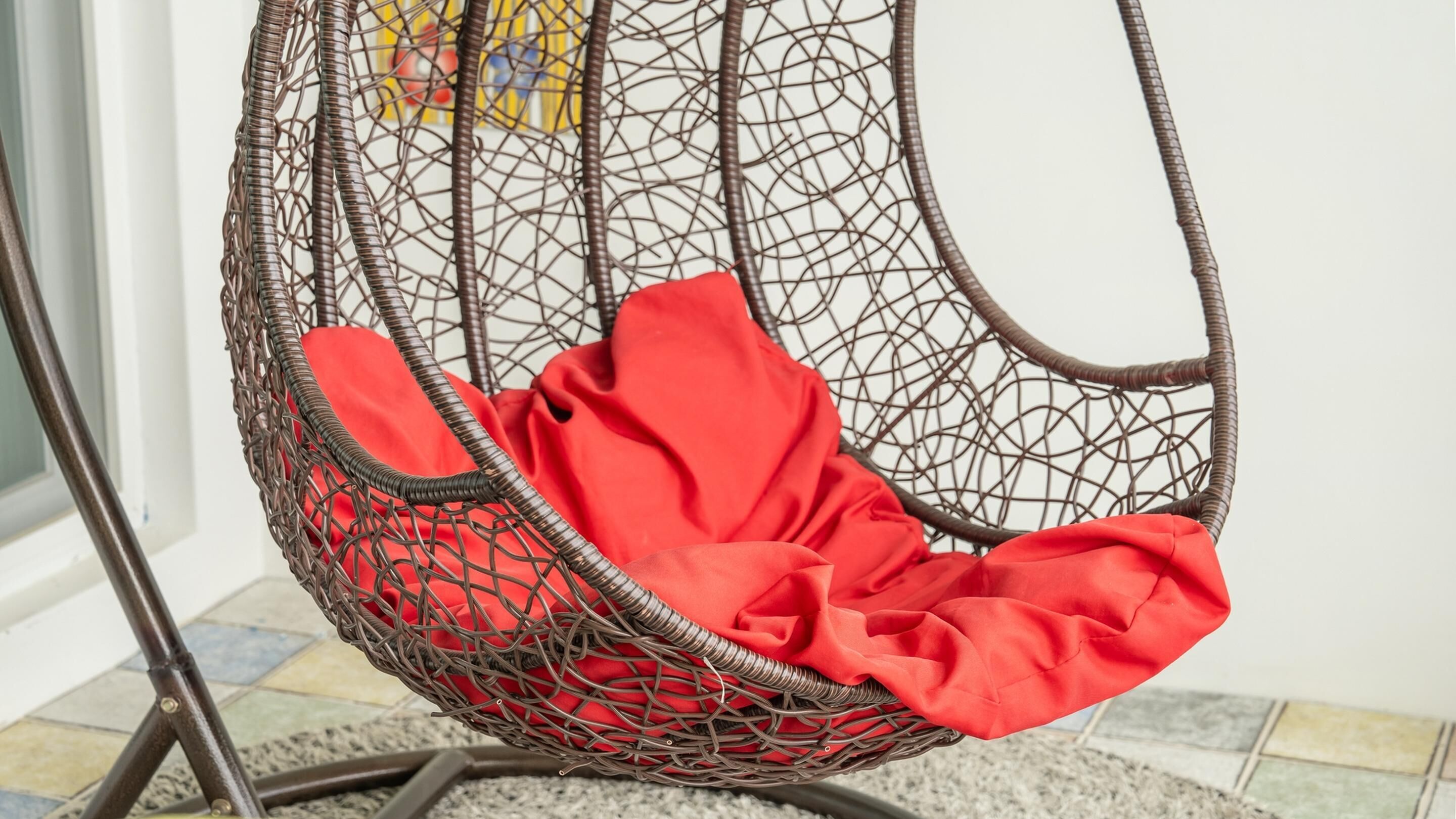 A wicker chair with a red cushion.