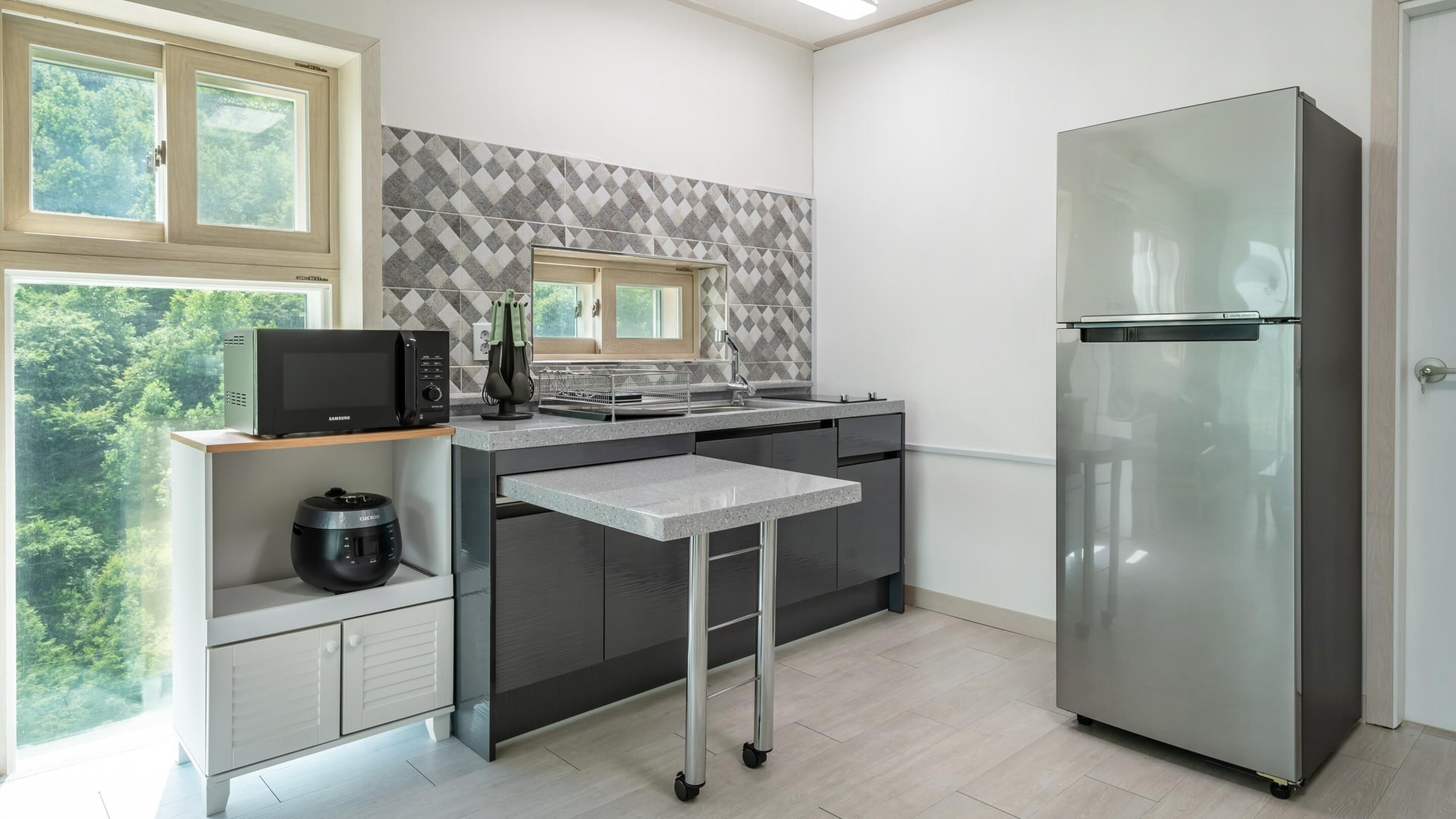 A modern kitchen with a built-in microwave, stainless steel refrigerator, and a kitchen island with a sink.
