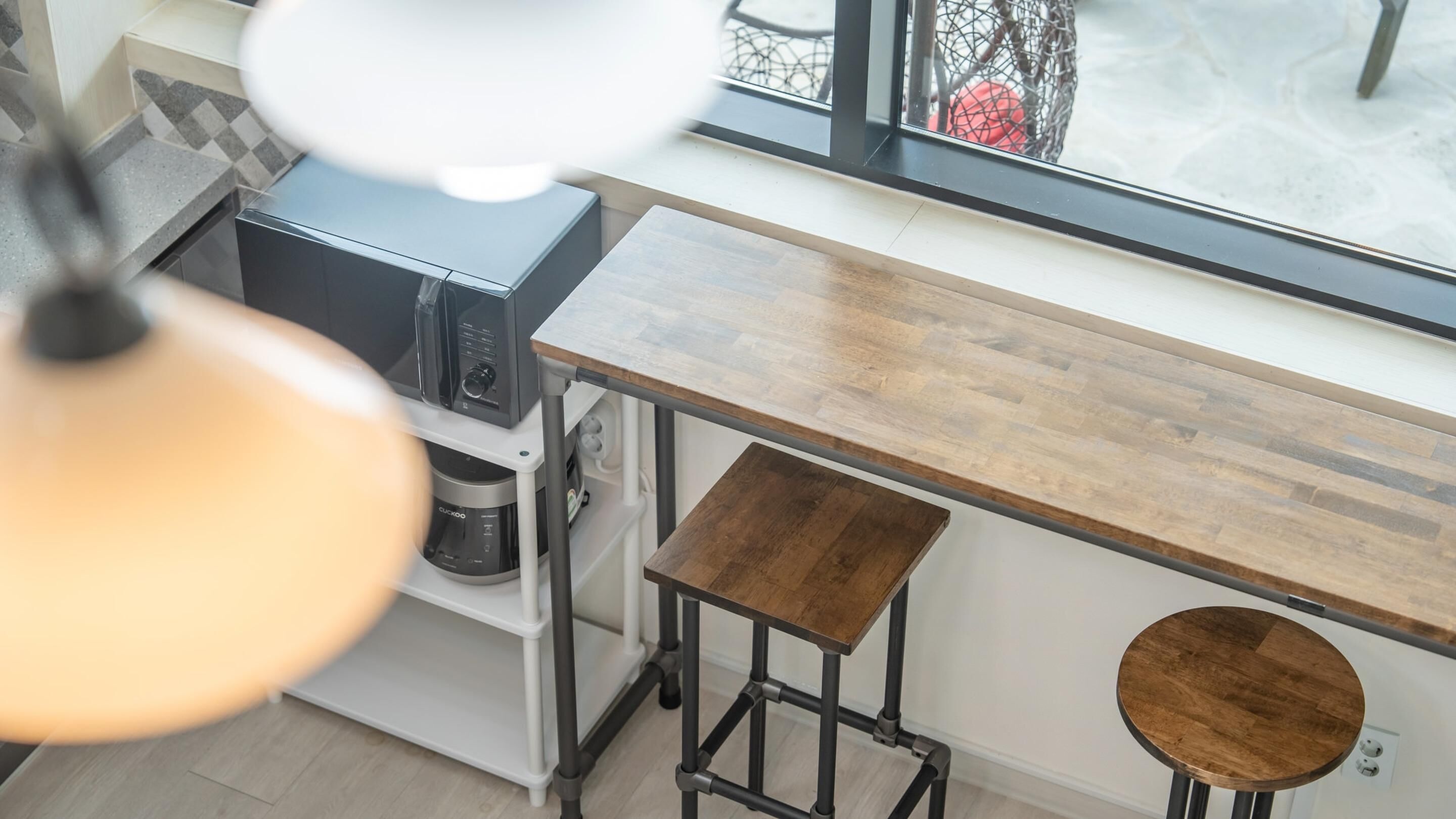 A kitchen with a wooden countertop, a coffee machine, and a hanging light fixture.