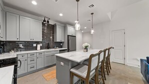 A modern kitchen with grey cabinets, a marble island, and pendant lighting.