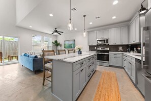 A modern kitchen with grey cabinets, a central island, and stainless steel appliances. - Cajun French House*2 King Beds*Fast Wi-Fi*Garage (Lafayette)