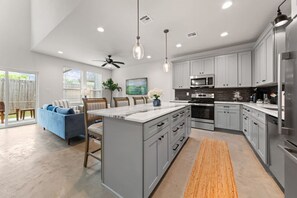 A modern kitchen with grey cabinets, a central island, and stainless steel appliances. - Cajun French House*2 King Beds*Fast Wi-Fi*Garage (Lafayette)