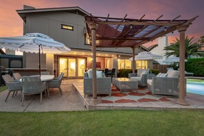 Een terras met tuinmeubilair, een zwembad en een overdekt zitgedeelte.