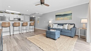 Ein modernes Wohnzimmer mit einem blauen Sofa, einem Couchtisch und einer Küchenzeile mit Barhocker.