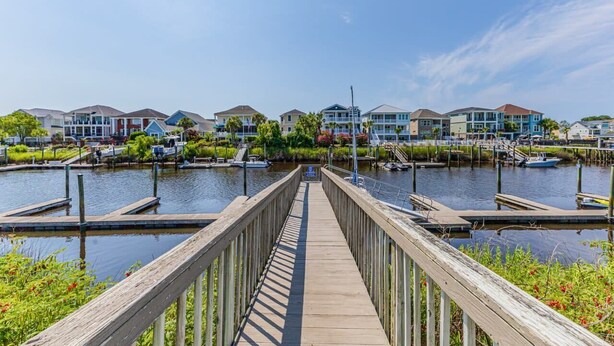 A wooden pier leading to a marina with boats docked, surrounded by multi-story buildings with balconies. - Carolina Yacht A2 Sum (Little River)