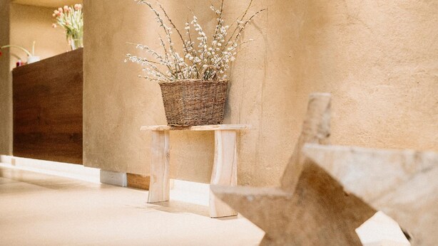 A wicker basket with branches on a white pedestal in a hallway. - Kurhotel San Andreas (Bad Fuessing)