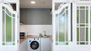 A compact kitchen with a washing machine, a microwave, and a sink. - "Apartamentos Bestarruza" - 2 rooms (Mugardos)