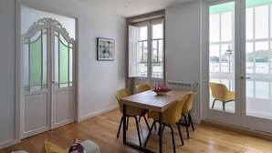Ein Essbereich mit Holztisch und gelben Stühlen, großen Fenstern mit Blick und einer Tür mit dekorativem Design.