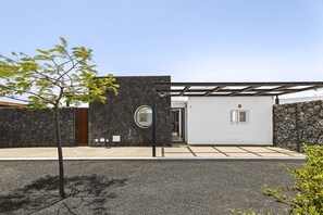 Ein modernes Gebäude mit Natursteinfassade, Holztür und überdachter Eingangszone.