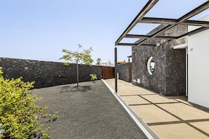 Eine moderne Außenpatio mit Steinmauer, Holztür und Glasbau.
