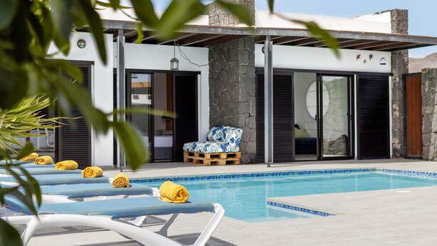 A modern pool area with lounge chairs and a stone wall.
