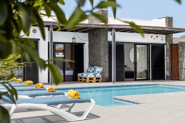 Ein moderner Poolbereich mit Liegestühlen und einer Steinmauer.