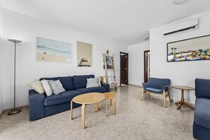Ein modernes Wohnzimmer mit einem blauen Sofa, zwei Holztischen und einem blauen Sessel.